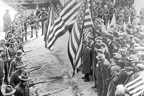 State militia troops challenge peaceful Lawrence, Mass., textile mill strikers led by the Industrial Workers of the World in 1912. Photo from Wikipedia.