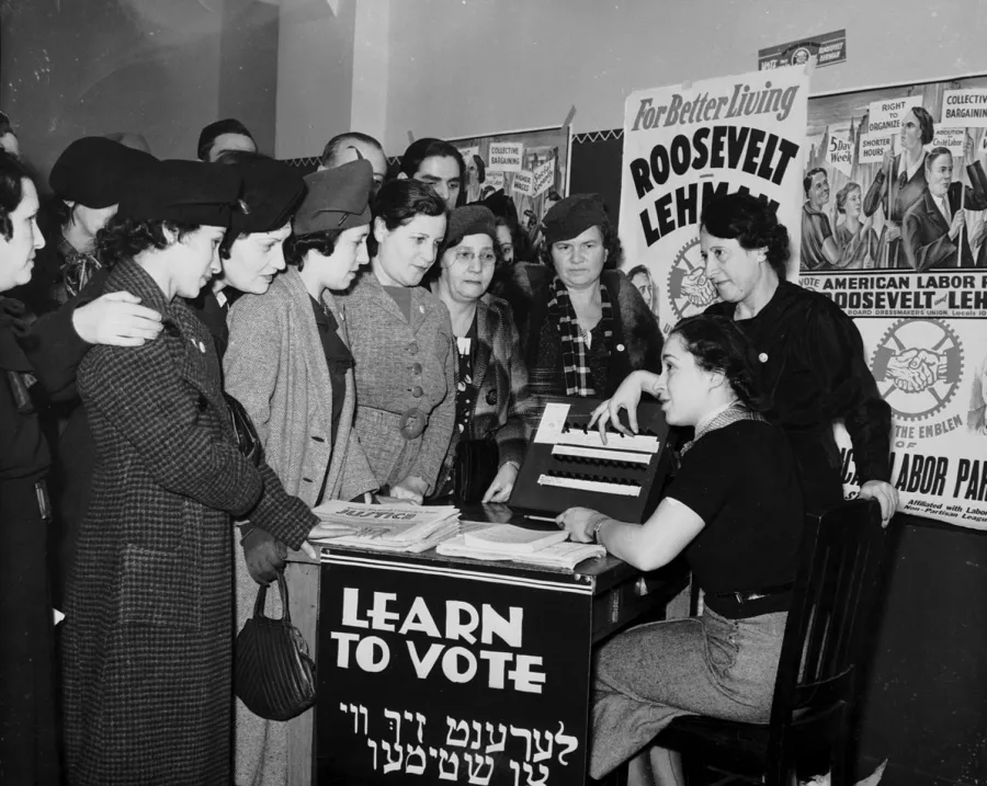 Women surrounded by posters in English and Yiddish supporting Franklin D. Roosevelt, Herbert H. Lehman, and the American Labor Party teach other women how to vote, 1935. International Ladies Garment Workers Union Photographs (1885-1985)